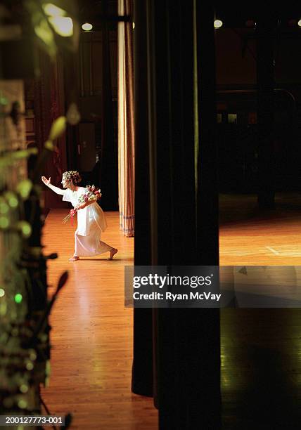 opera singer holding bouquet of flowers, taking bow on stage - opera stage stock-fotos und bilder