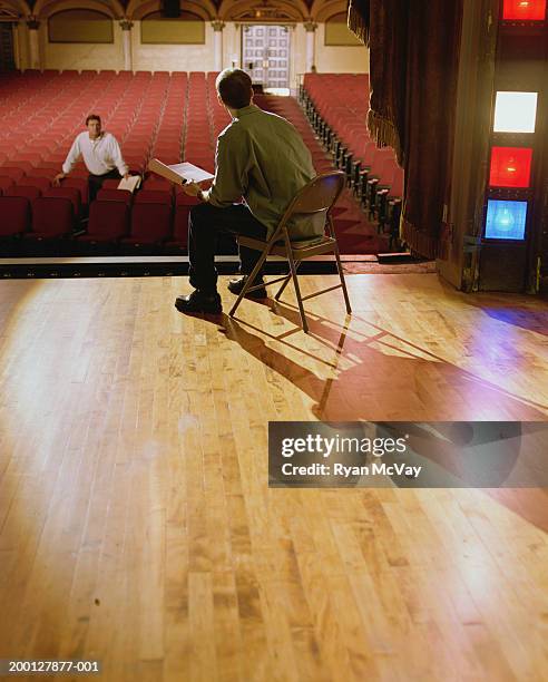 man speaking to actor sitting on stage - regista cinematografico foto e immagini stock
