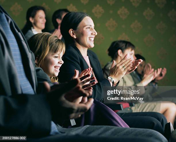 girl (6-8) sitting between parents, applauding at theater - children theatre foto e immagini stock