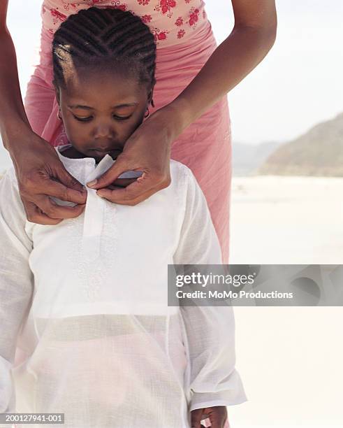 mother buttoning girl's (2-4) shirt at beach - knäppa knappar bildbanksfoton och bilder