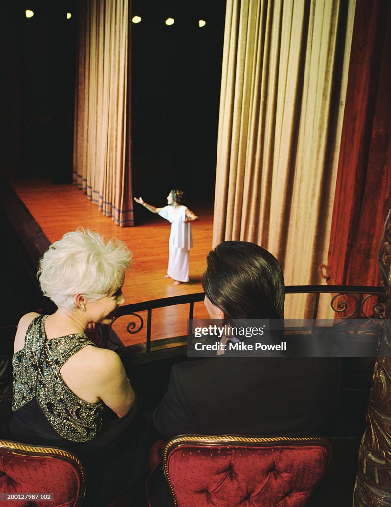 Couple sitting in balcony seats at opera, rear view