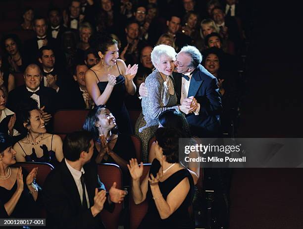 audience applauding mature woman, husband kissing cheek - prijsuitreikingsceremonie stockfoto's en -beelden