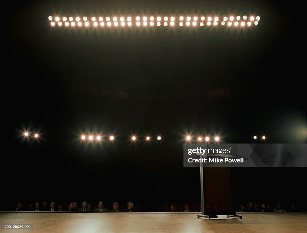 Empty podium on stage, audience in background