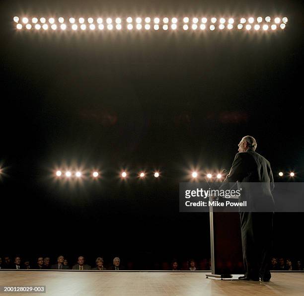 business executive standing behind podium on stage - discorso foto e immagini stock