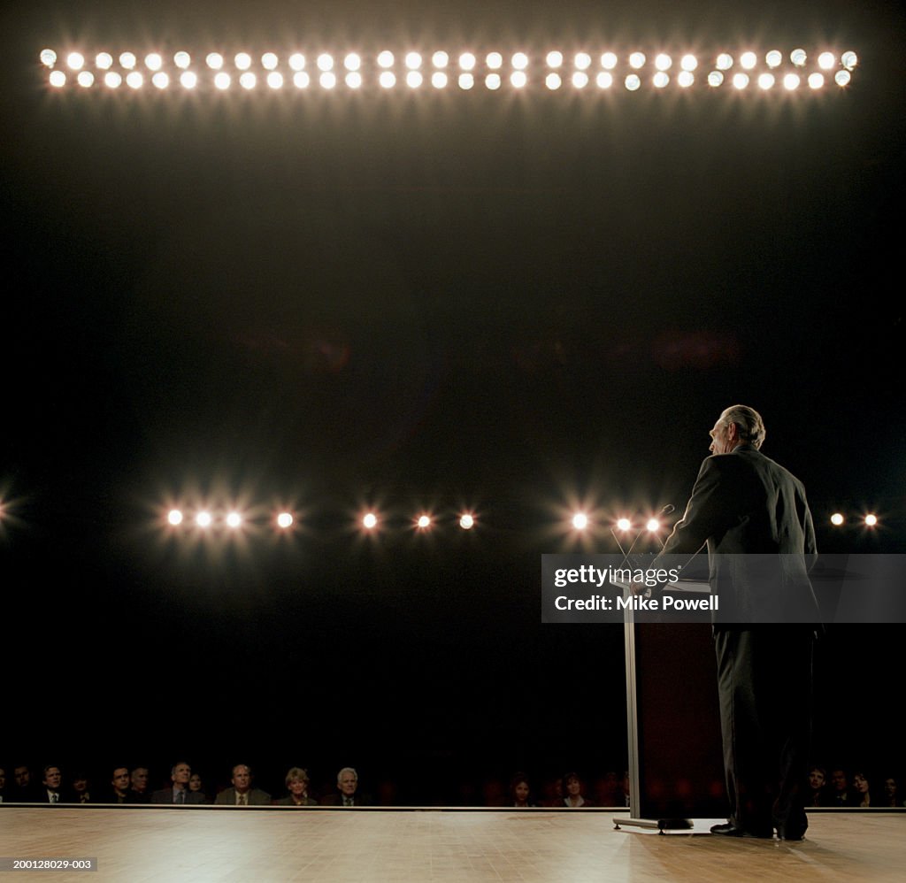 Business executive standing behind podium on stage
