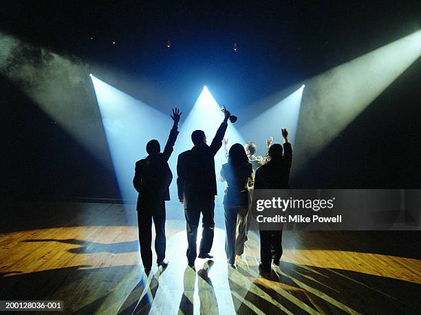 business executives walking on stage towards spotlight, holding award - five people stock-fotos und bilder