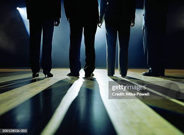 business executives standing on stage facing spotlight, rear view - spia foto e immagini stock