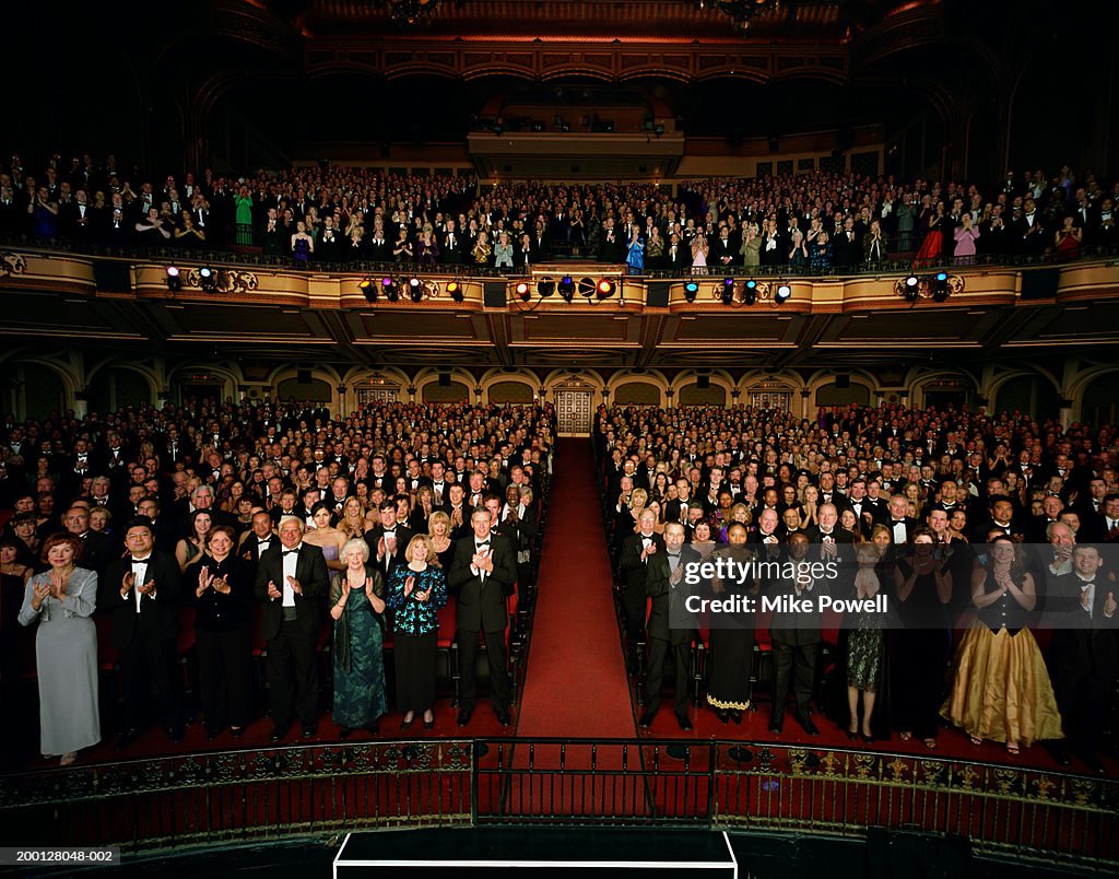 Theater audience standing in formal attire, applauding