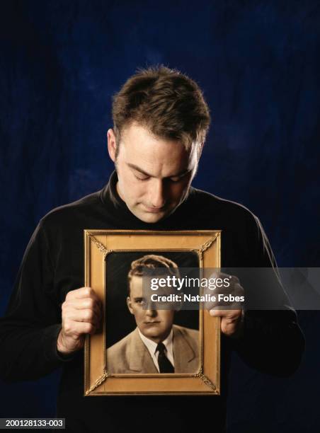 man holding framed photograph of young man - holding photo stock pictures, royalty-free photos & images