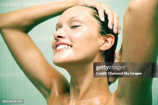 young woman taking shower, hands on head, smiling, close-up - femme shampoing photos et images de collection