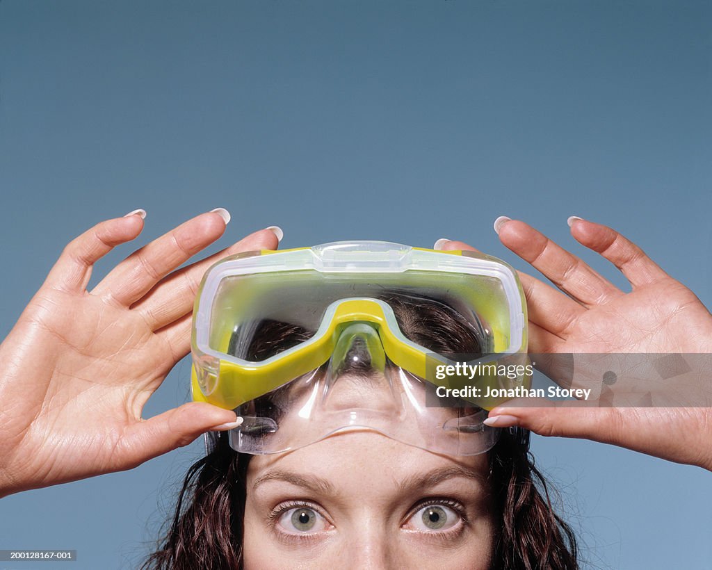 Woman holding scuba mask on forehead, portrait, close-up, high section