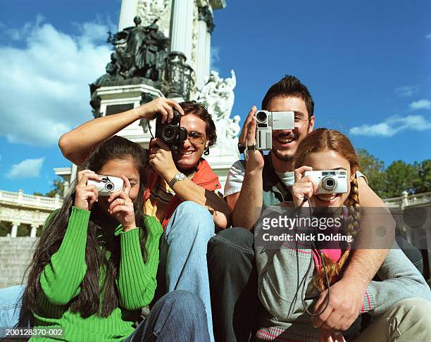 four friends using camcorder and cameras, outdoors - travel2 stock pictures, royalty-free photos & images