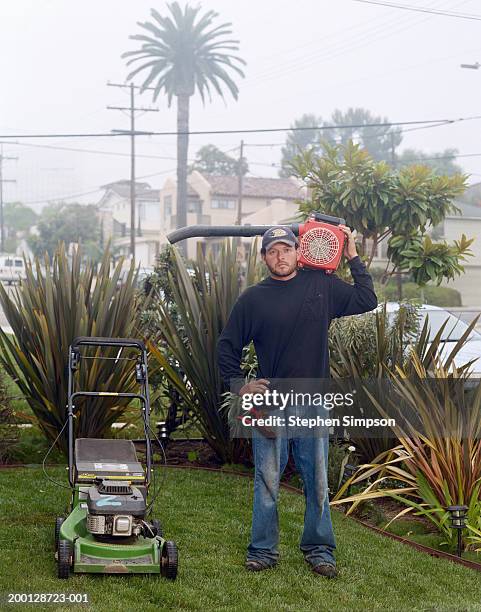 man holding leaf blower, standing next to lawnmower, portrait - leaf blower stock pictures, royalty-free photos & images