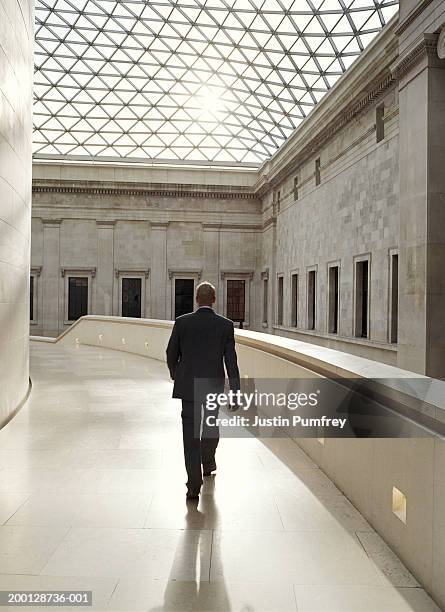 businessman walking in glass-roofed building - bloomsbury london stock-fotos und bilder