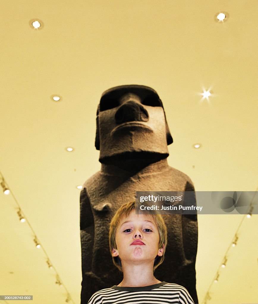 Boy (7-9) mimicking expression on face of statue, portrait