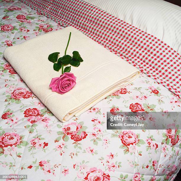rose and towel on floral patterned bedspread - travel2 stock pictures, royalty-free photos & images