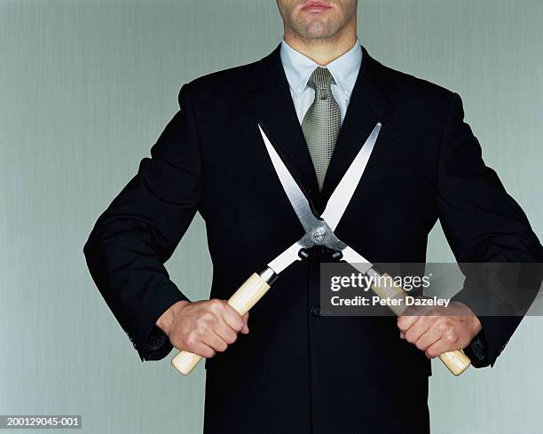 businessman holding garden shears, mid section - kosten besparen stockfoto's en -beelden