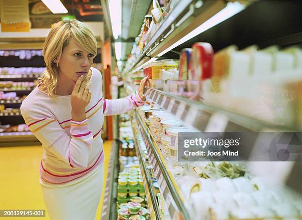 young woman looking at dairy produce in supermarket - woman supermarket stockfoto's en -beelden