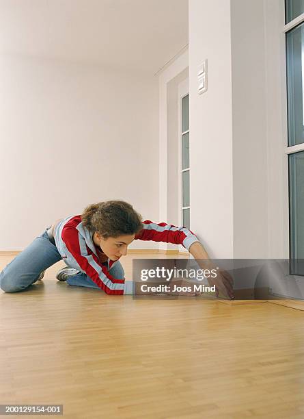 young woman measuring skirting board in empty room - panela bildbanksfoton och bilder