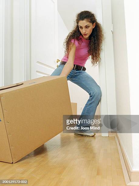 young woman pulling box towards doorway - minimal effort stock pictures, royalty-free photos & images