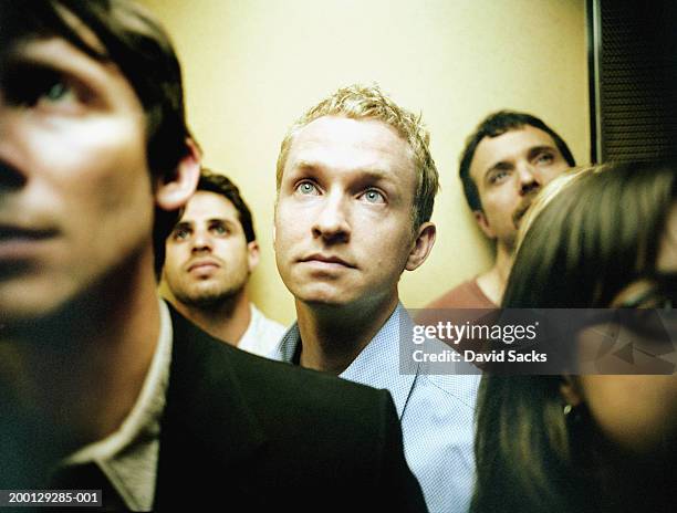 people in elevator, close up (focus on blond man) - huddle ストックフォトと画像