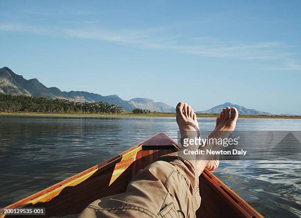 young man lying in boat on lake, low section - personal perspective or pov ストックフォトと画像