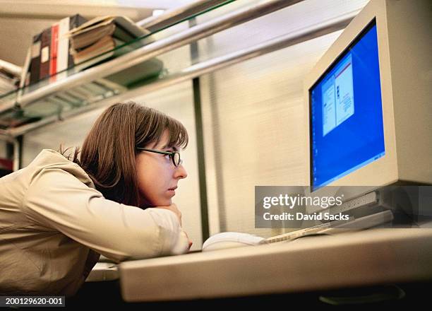 woman resting head on arms, looking at computer monitor in office - cross bores stock pictures, royalty-free photos & images