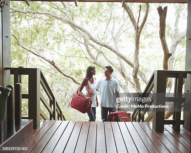 young couple at foot of steps to lodge - suitcase couple stock-fotos und bilder