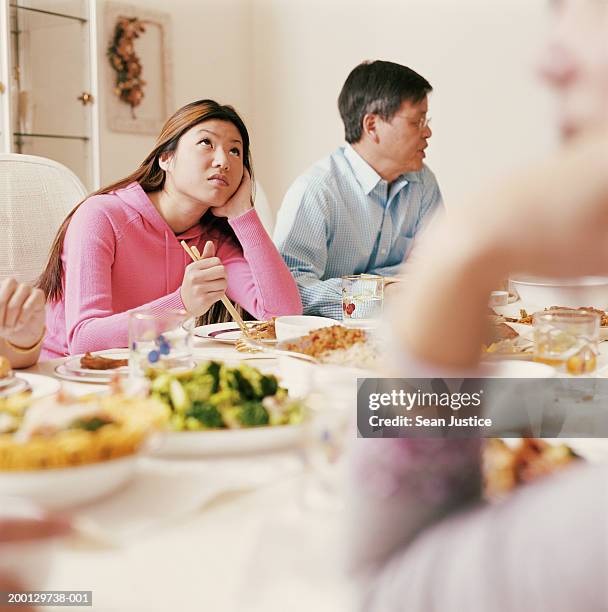 teenage girl (16-18) at family dinner looking upward - chinese family dinner stock-fotos und bilder