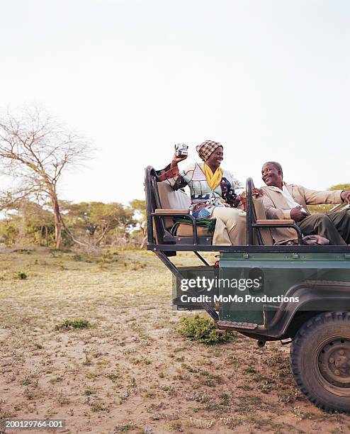 mature couple in 4x4 on safari, woman holding camera - südafrika safari stock-fotos und bilder