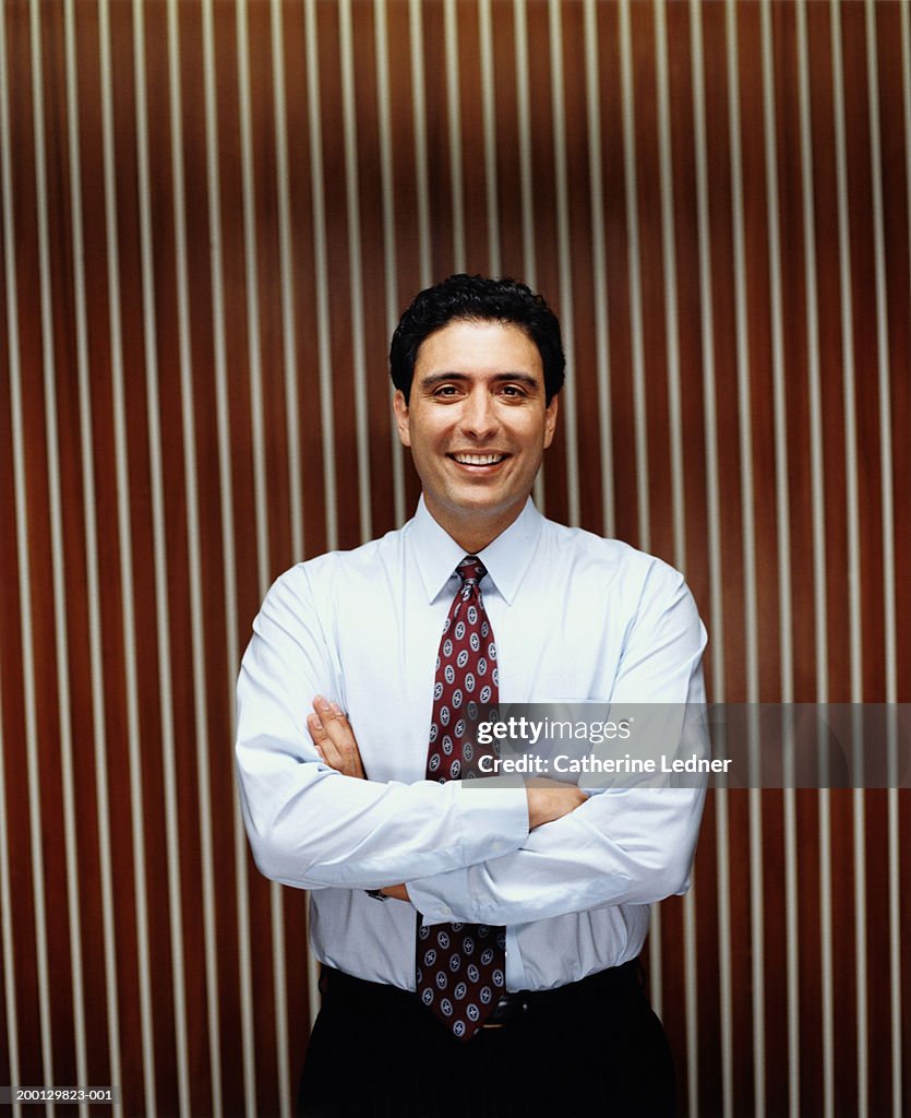 Businessman with arms crossed, smiling, portrait