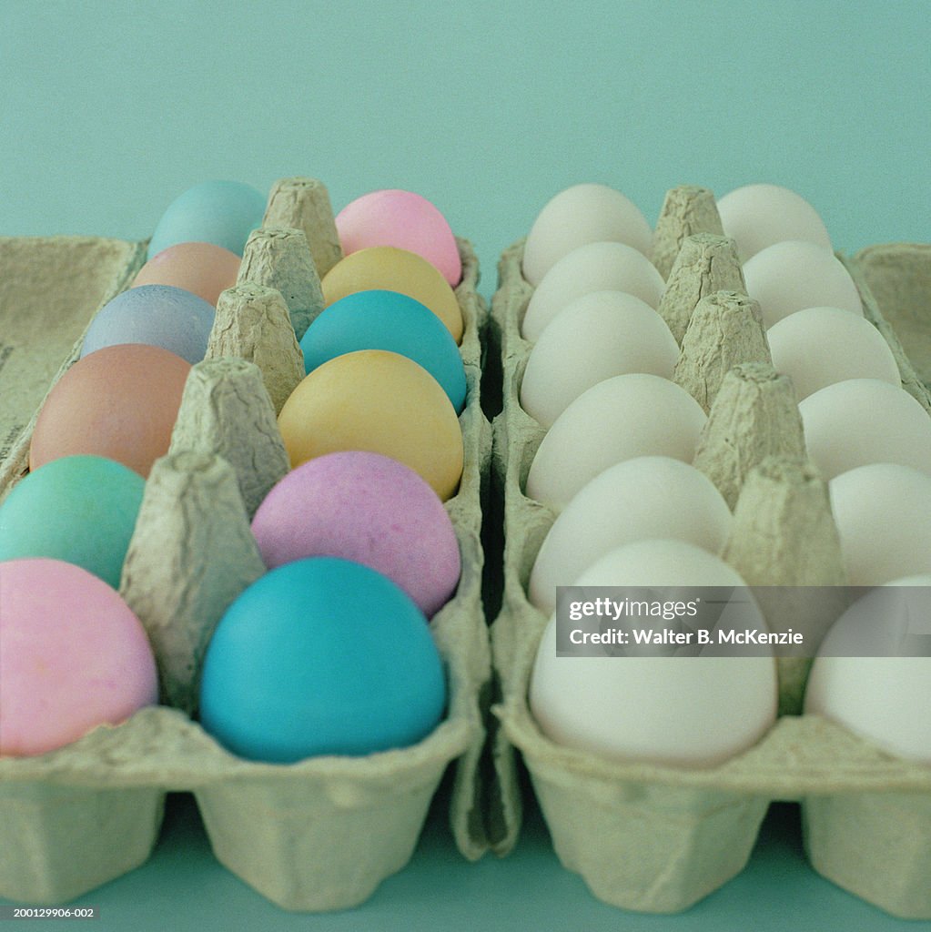 Carton of white eggs sitting next to carton of dyed Easter eggs