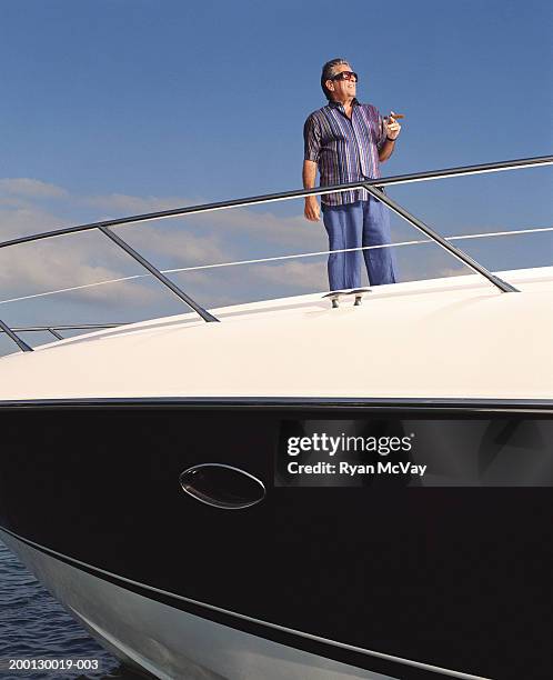 reifer mann hält zigarre auf yacht - cigar stock-fotos und bilder