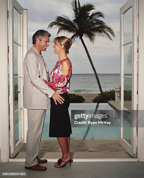 mature couple face to face by open doors to veranda, side view - french doors stock pictures, royalty-free photos & images