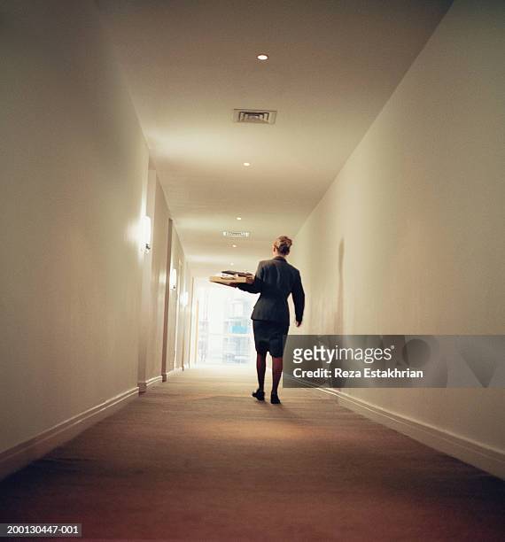room service attendant carrying tray down hallway, rear view - serviços de limpeza imagens e fotografias de stock