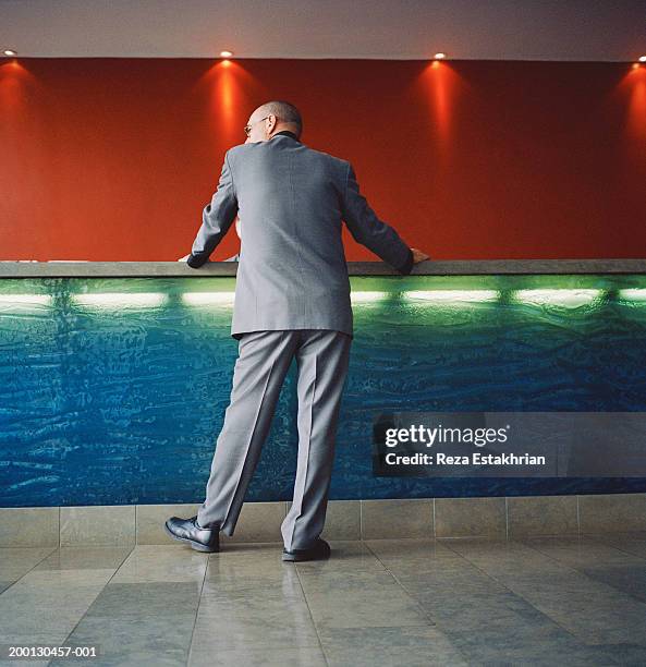 businessman standing at hotel front desk, low angle view - stoneplus1 stock pictures, royalty-free photos & images