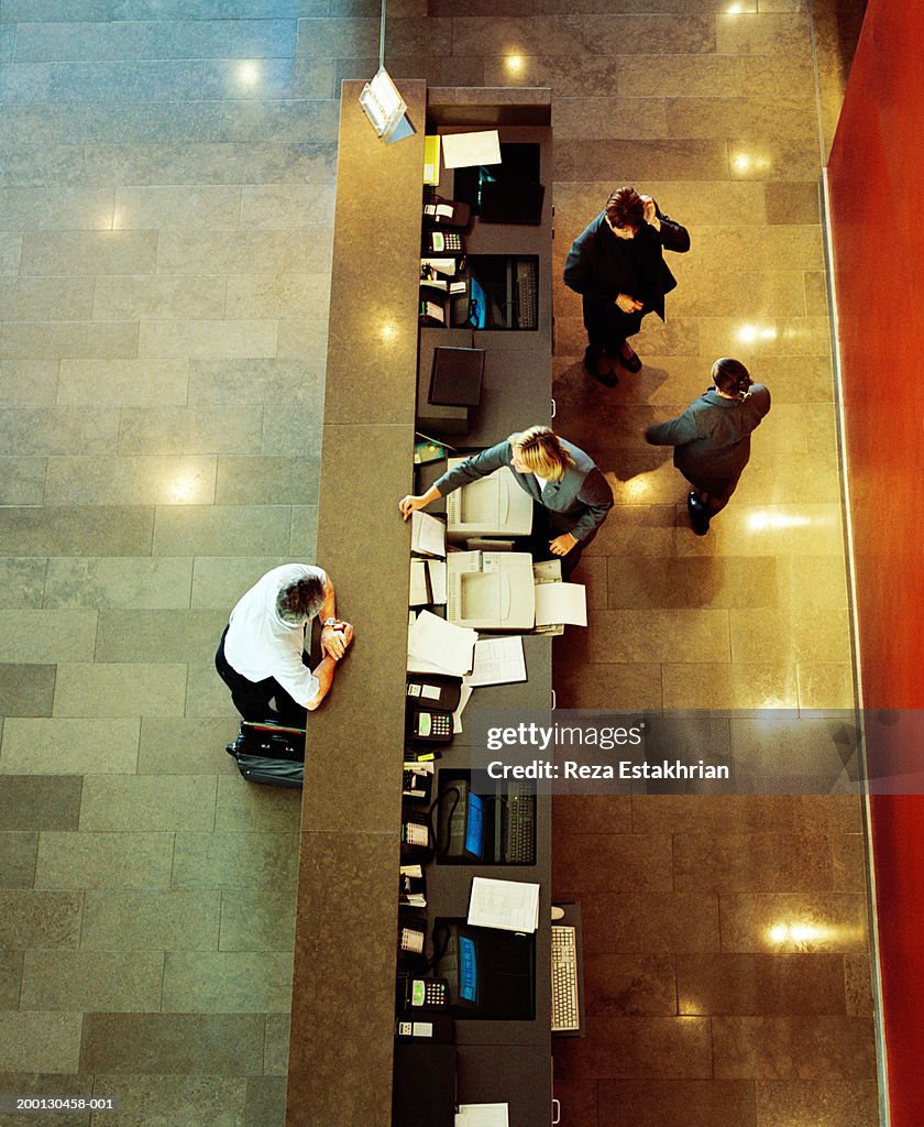 Businessman standing at hotel reception desk, overhead view