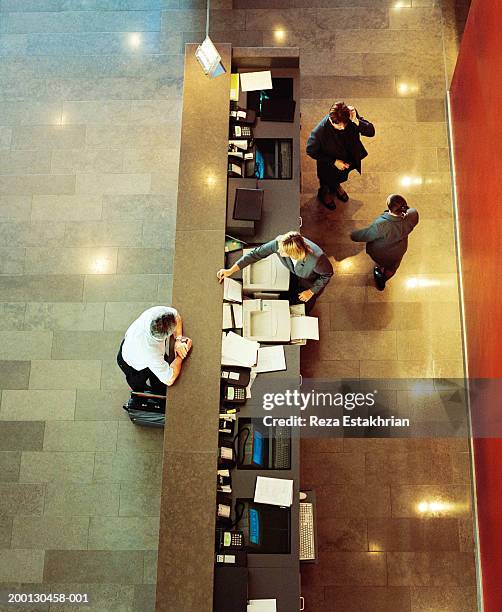 businessman standing at hotel reception desk, overhead view - hotel staff stock pictures, royalty-free photos & images