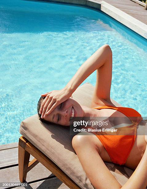 woman lying on chair near swimming pool, smiling - tomar el sol fotografías e imágenes de stock