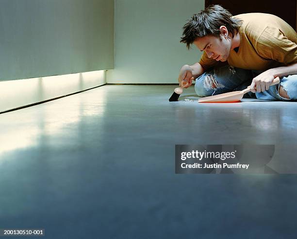 young man sweeping floor with dust pan and brush - obsession photos et images de collection