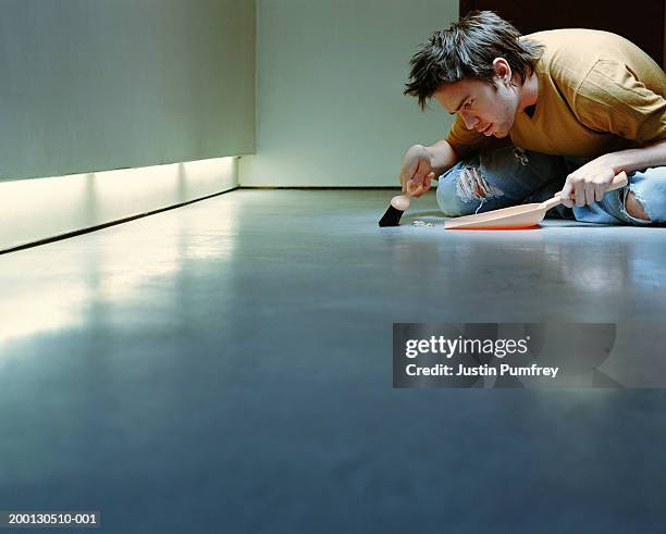 young man sweeping floor with dust pan and brush - obsessive stockfoto's en -beelden