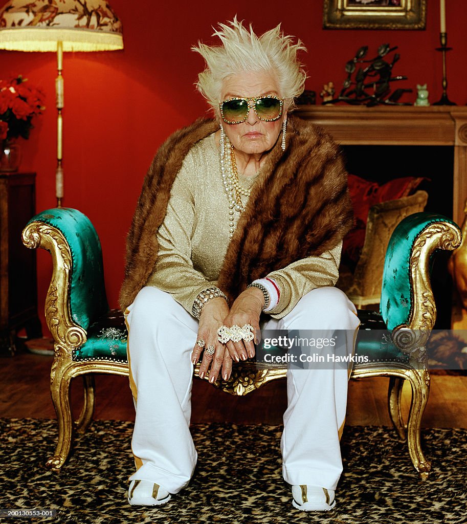 Senior woman on chaise longue, wearing hip hop accessories, portrait