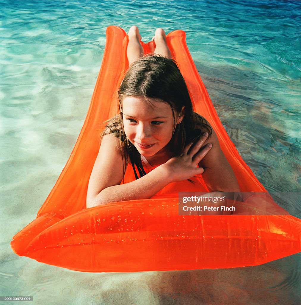 Girl (8-10) lying on inflatable raft