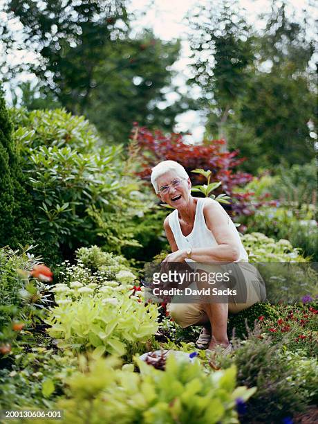 mature woman working in garden, smiling, portrait - pantalon stockfoto's en -beelden