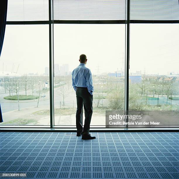 businessman looking out of office window, rear view - selective focus foto e immagini stock
