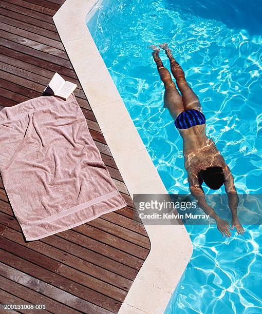 young man swimming, towel and book at pool edge, elevated view - young men in speedos 個照片及圖片檔