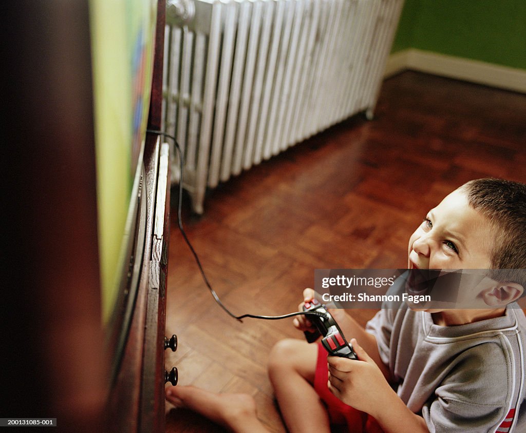Boy (5-7) playing video game on television, elevated view