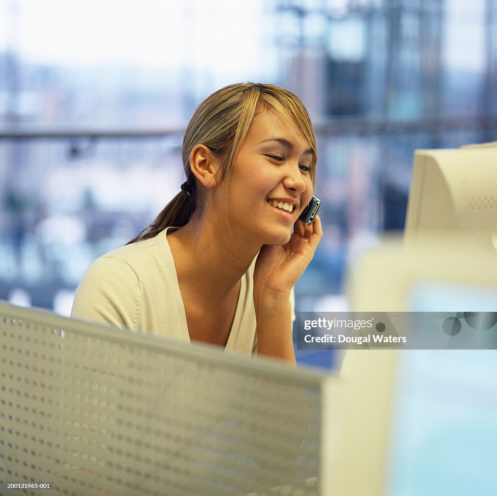 Teenage girl (15-17) using mobile phone at desk