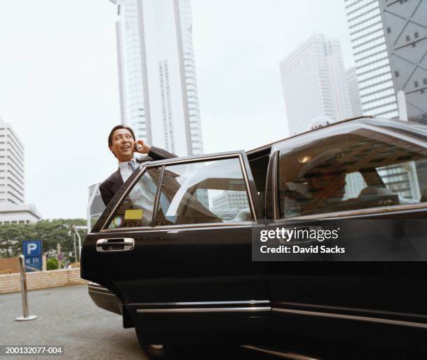 mature businessman using mobile phone exiting limousine - limousine exterior stock pictures, royalty-free photos & images