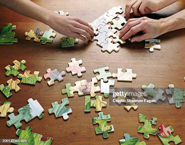 people putting puzzle together, close-up - puzzel stockfoto's en -beelden